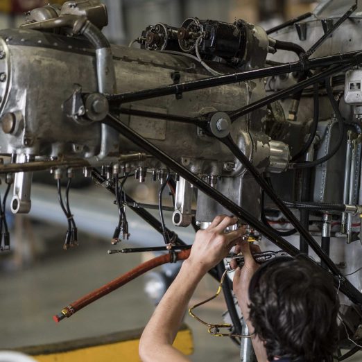 Crop hands of aircraft mechanic fixing engine of small airplane in hangar