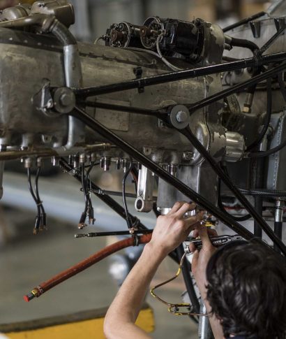 Crop hands of aircraft mechanic fixing engine of small airplane in hangar